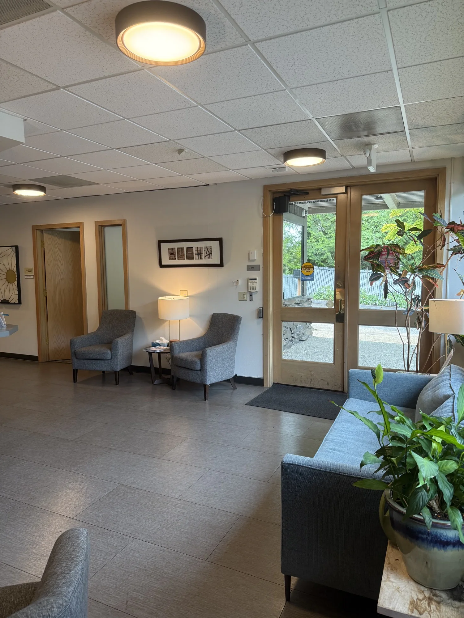 First-floor entry with glass doors, seating, and plants